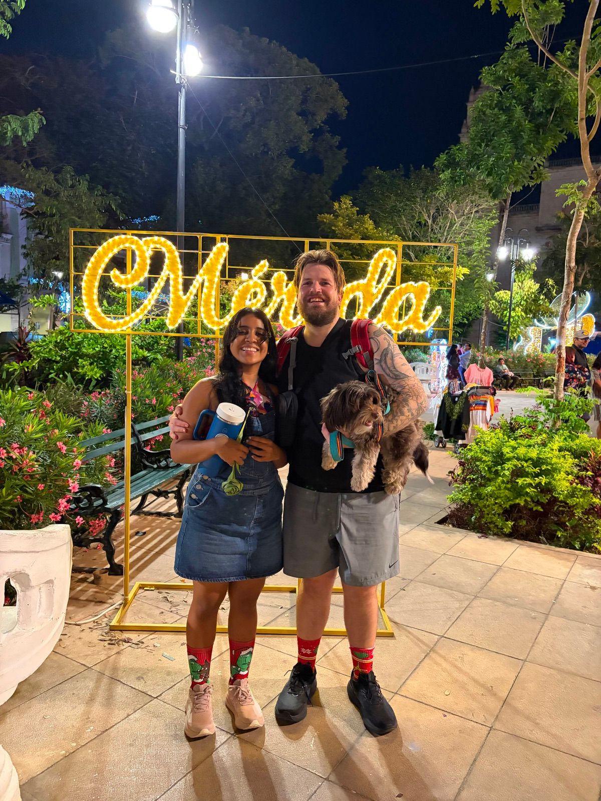 Sam and Blanca with their dog in front of a Mérida sign in the city